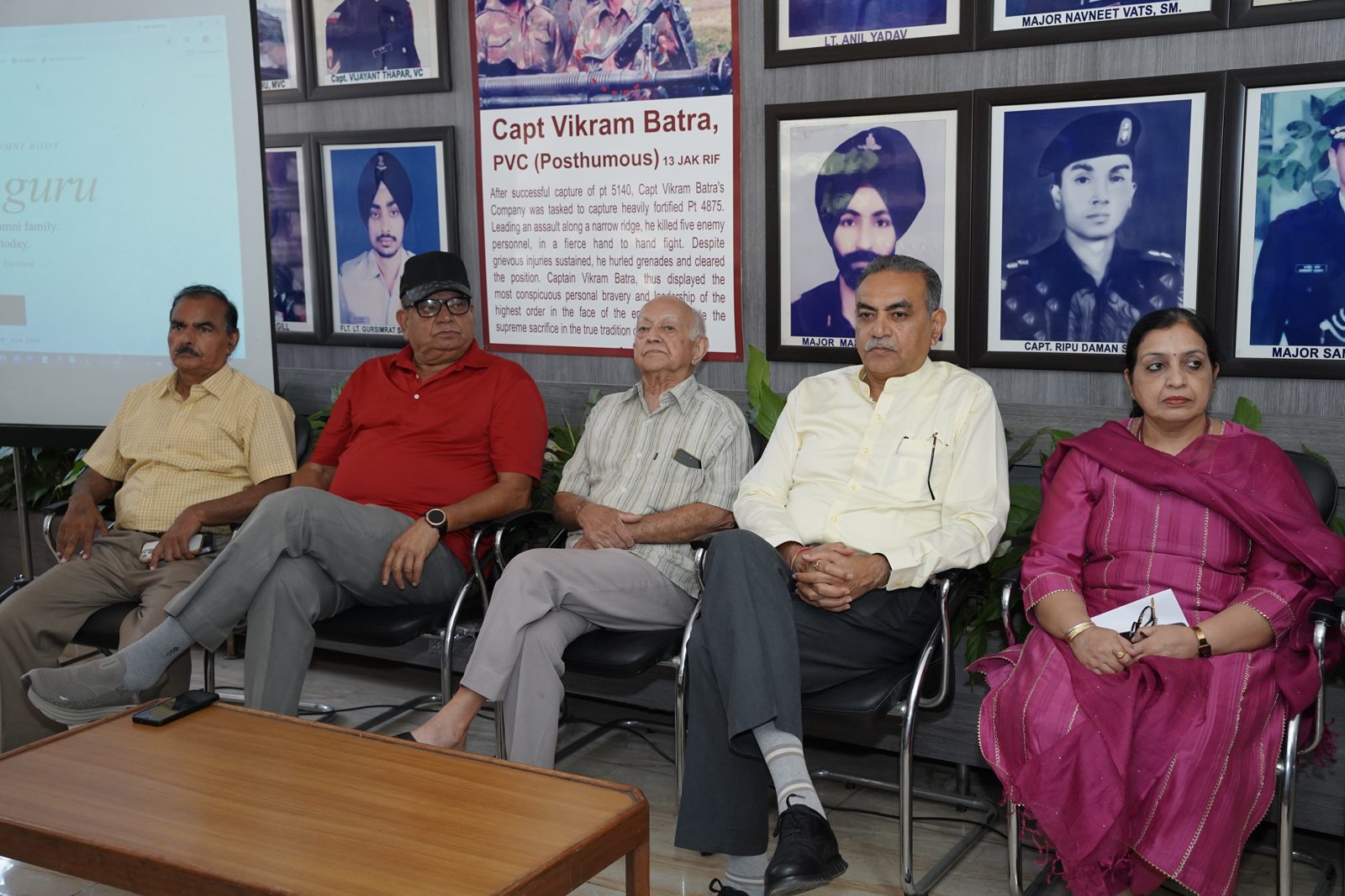 Dignitaries on the dais, beneath the college's wall honouring its military heroes.